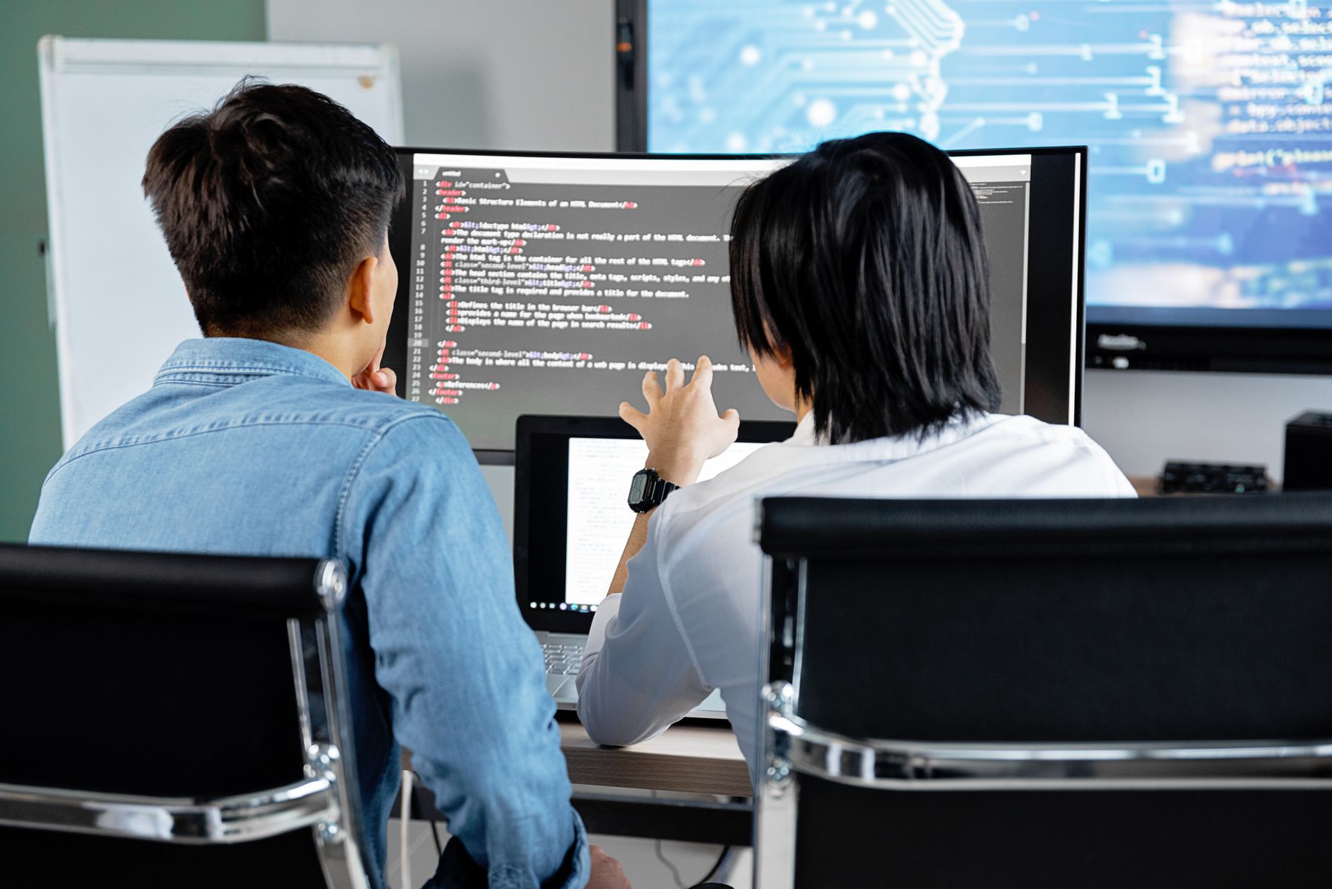 Dos programadores revisando código en una oficina. Photo by Mikhail Nilov on Pexels.