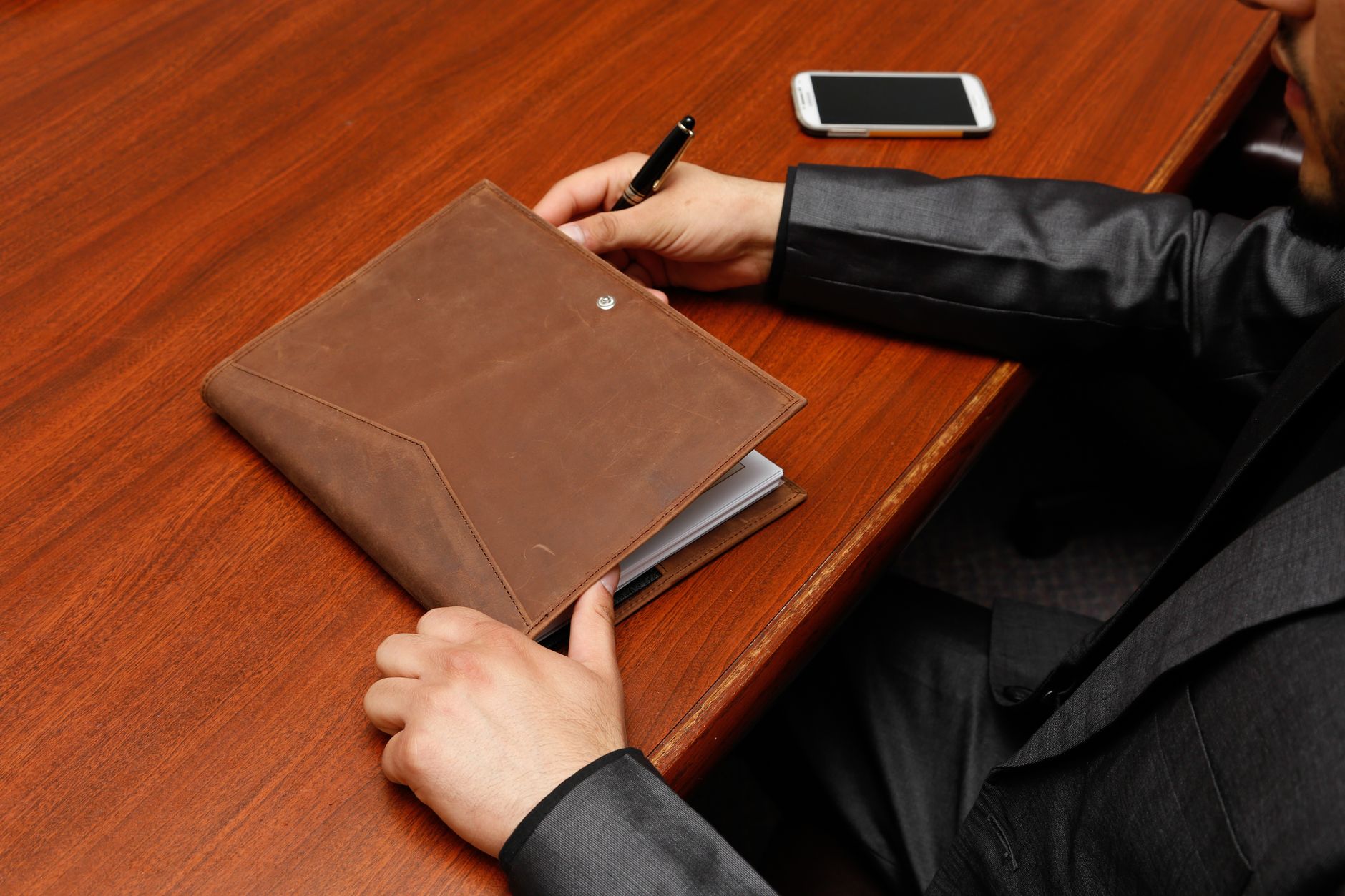 Persona escribiendo en un cuaderno sobre un escritorio. Photo by Pixabay on Pexels.