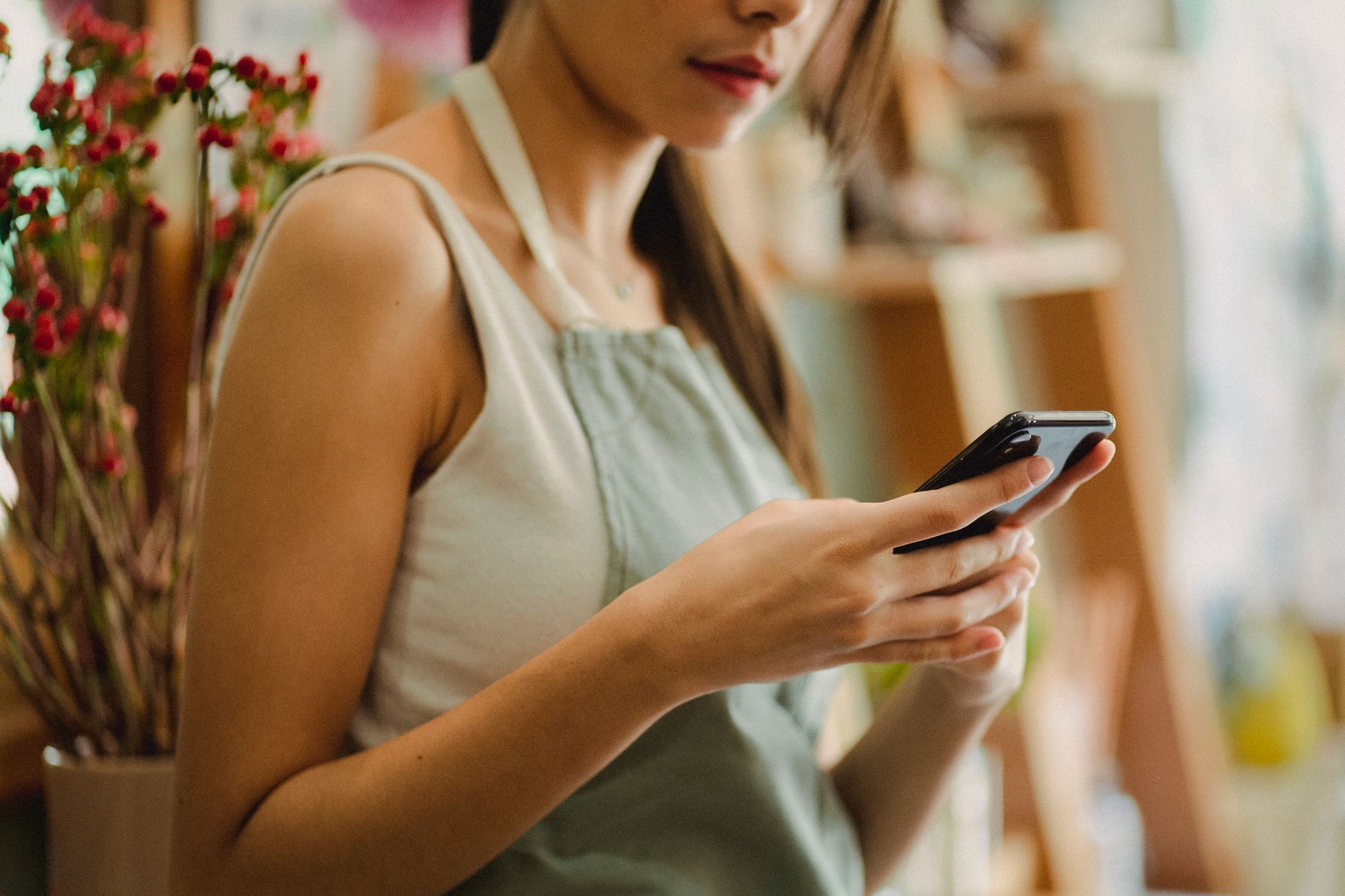 Dueña de negocio revisando su teléfono en su tienda. Photo by Amina Filkins on Pexels.